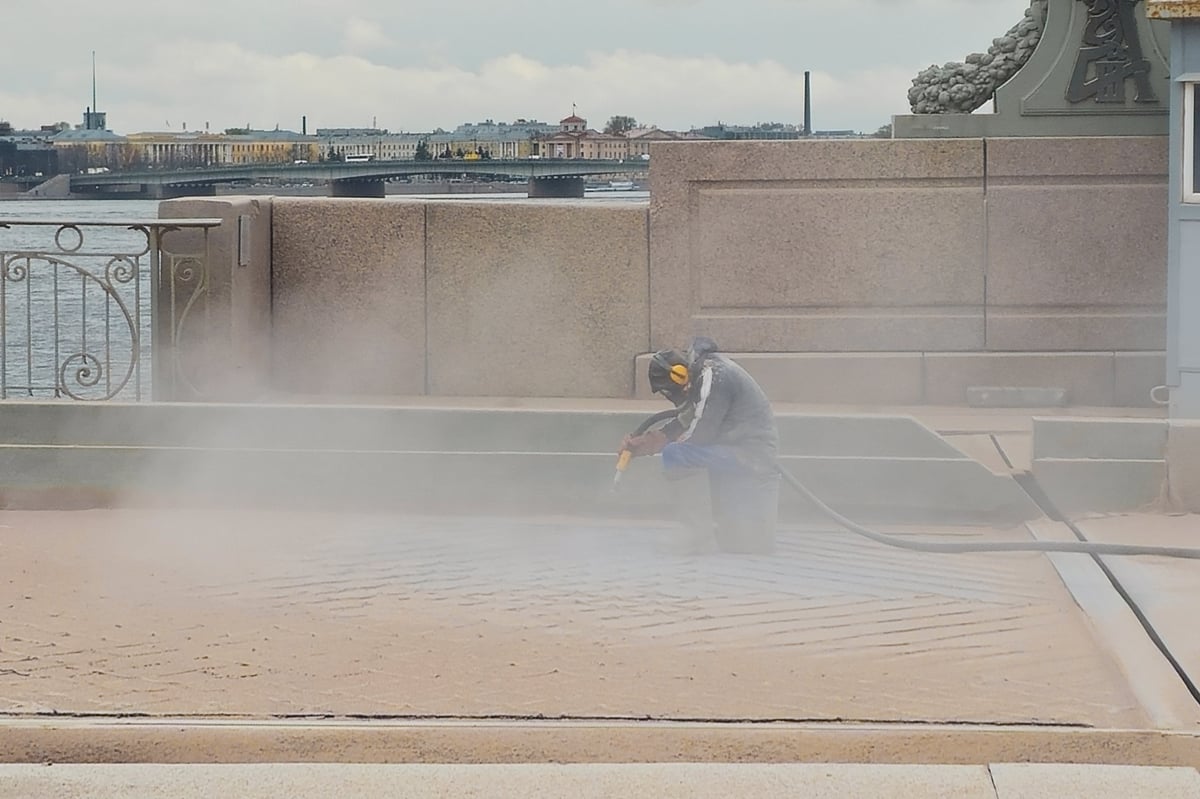 Worker performing blast cleaning on a steel structure, dust cloud in the air